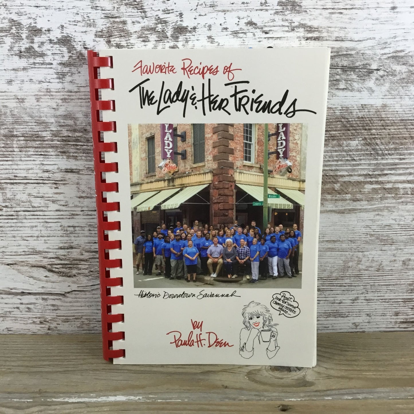 Cookbook titled 'Favorite Recipes of The Lady & Her Friends' on a wooden surface