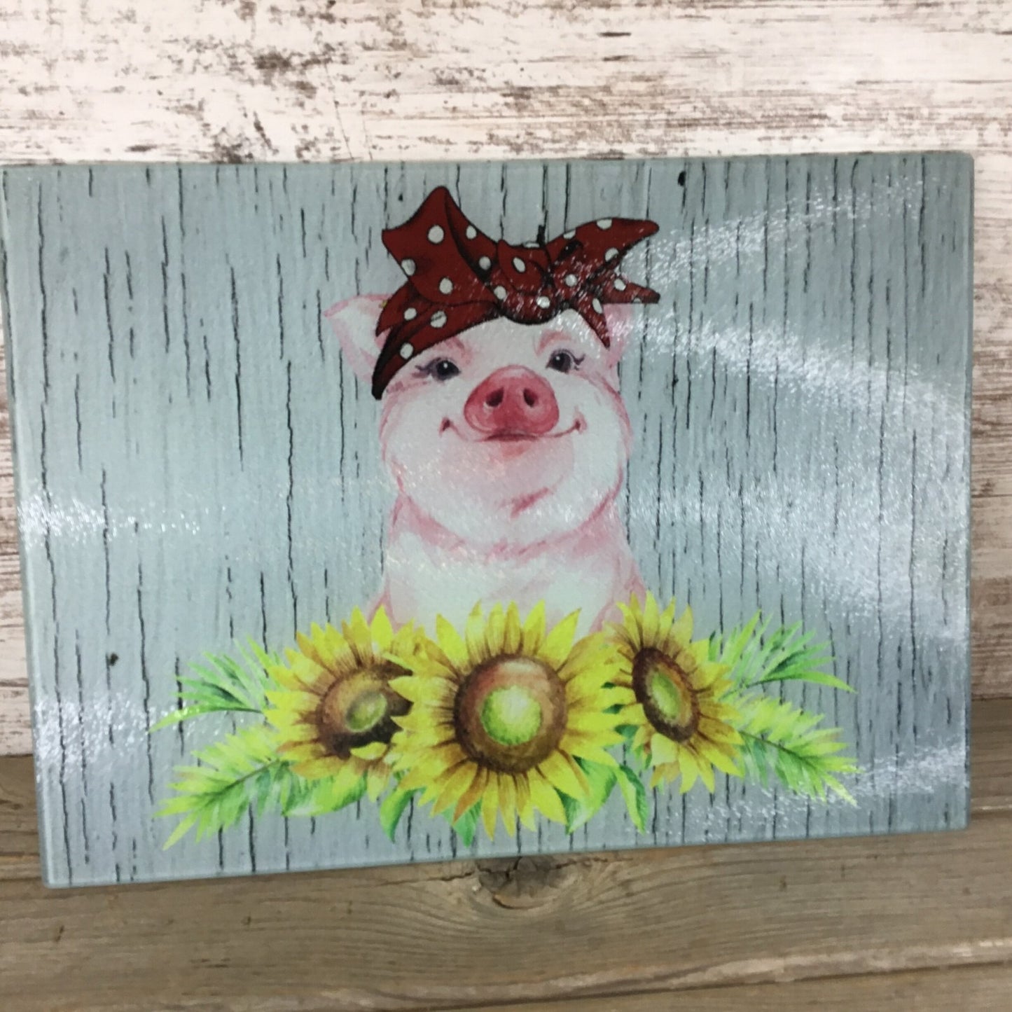 Painting of a pig with a bow and sunflowers on a wooden background