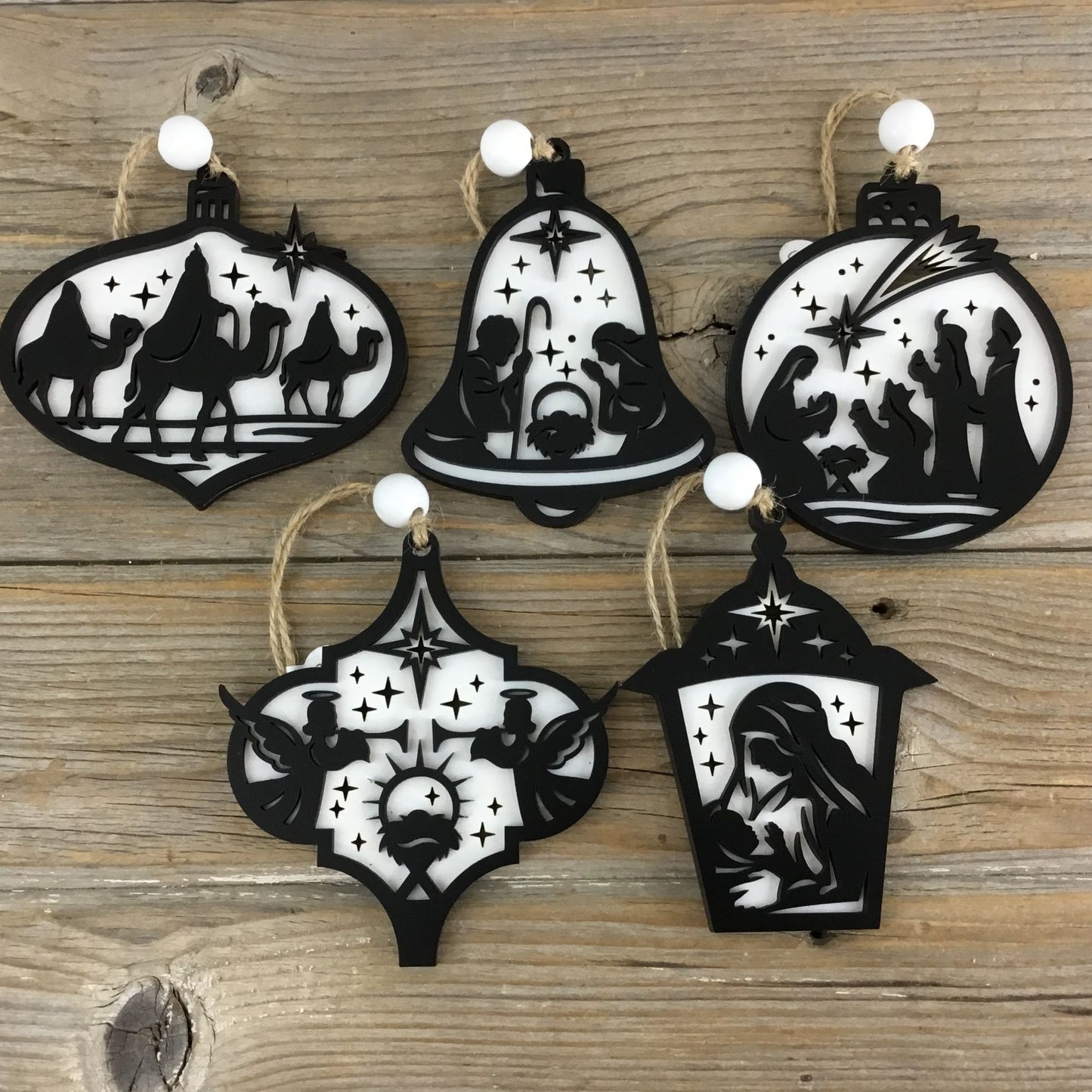 Set of five black and white nativity scene Christmas ornaments on a wooden background