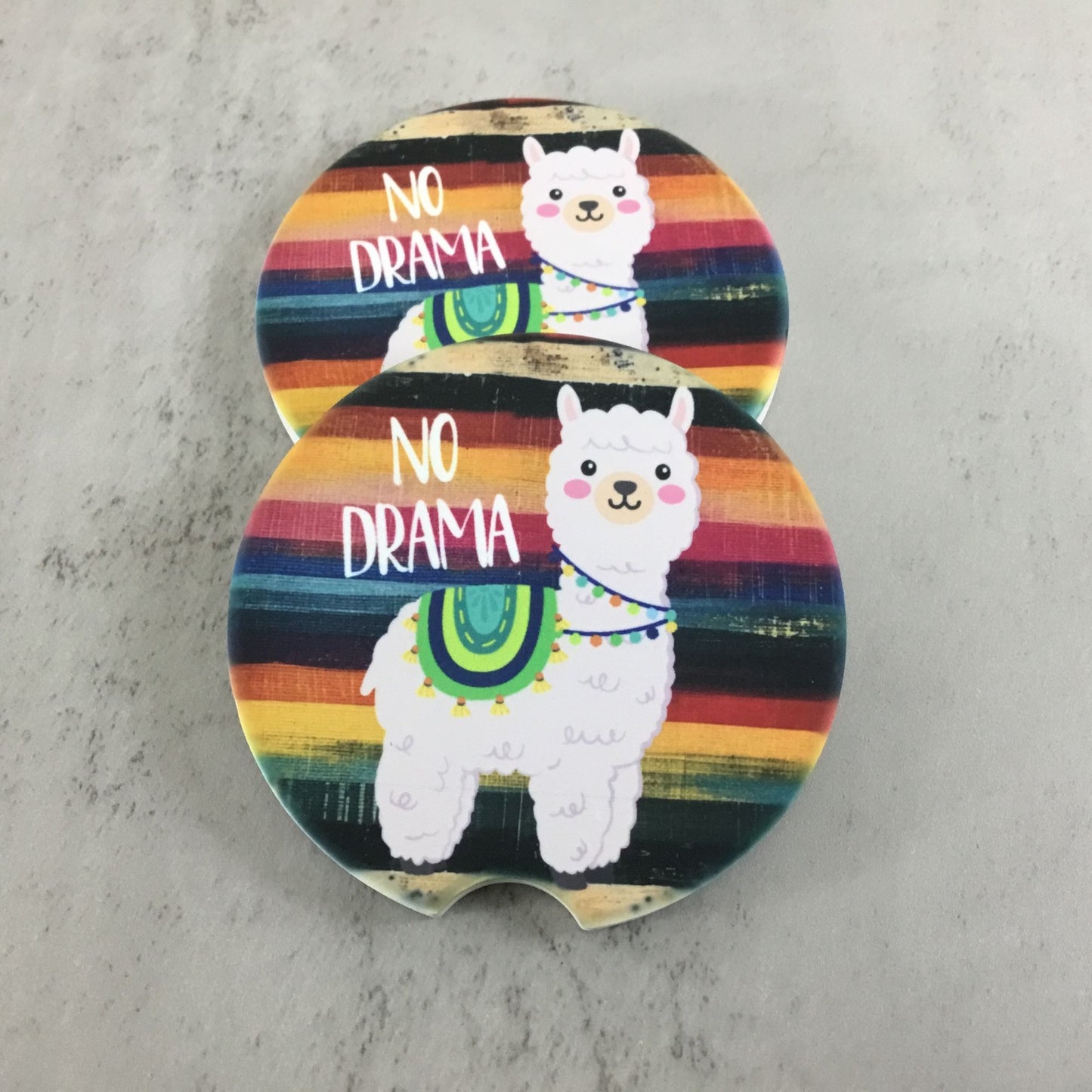 Two colorful coasters with llamas and 'No Drama' text on a gray surface.