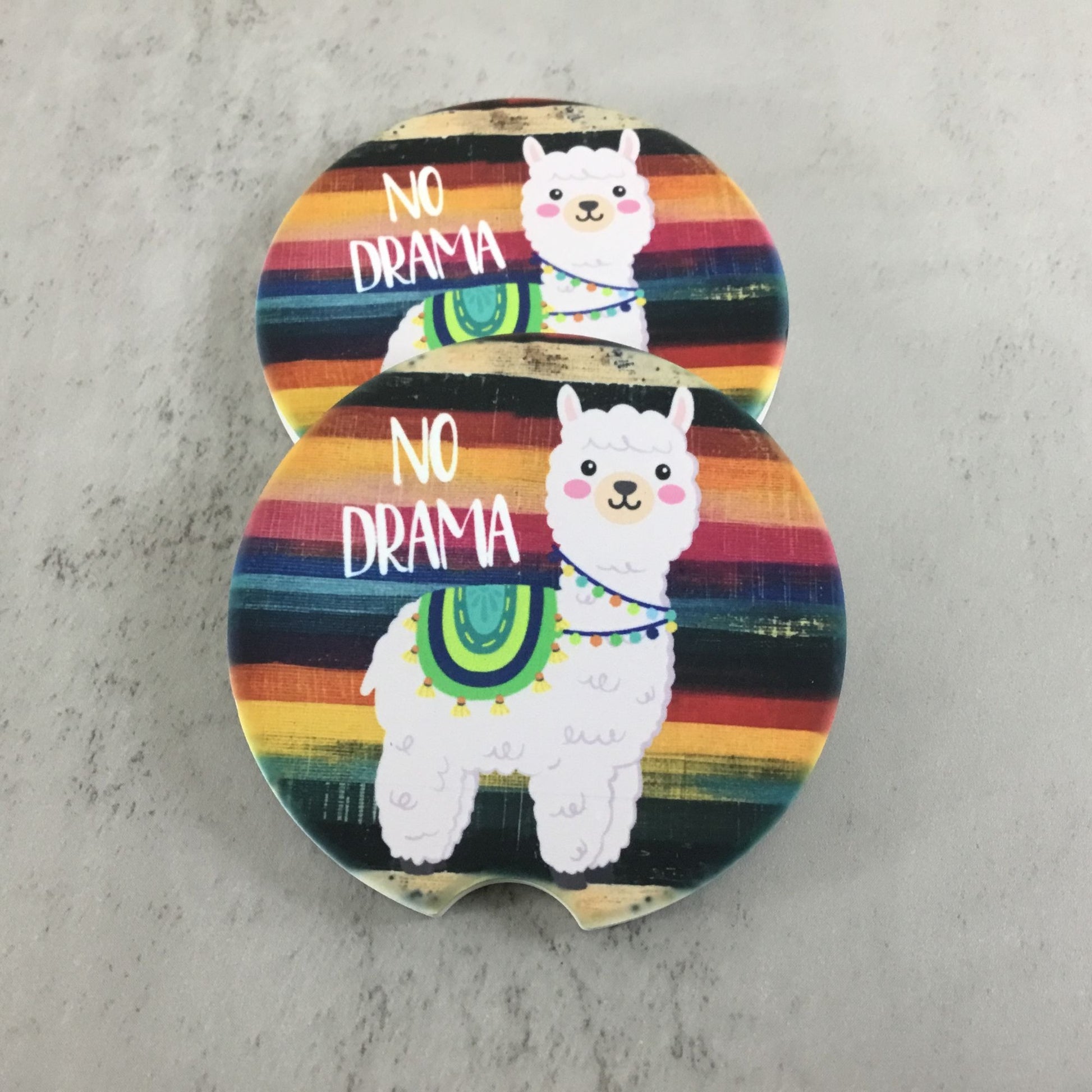 Two colorful coasters with llamas and 'No Drama' text on a gray surface.