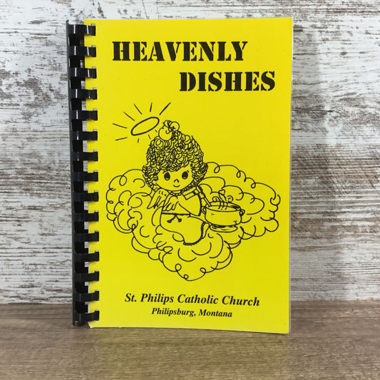 Notebook titled 'Heavenly Dishes' from St. Philip's Catholic Church on a wooden surface.