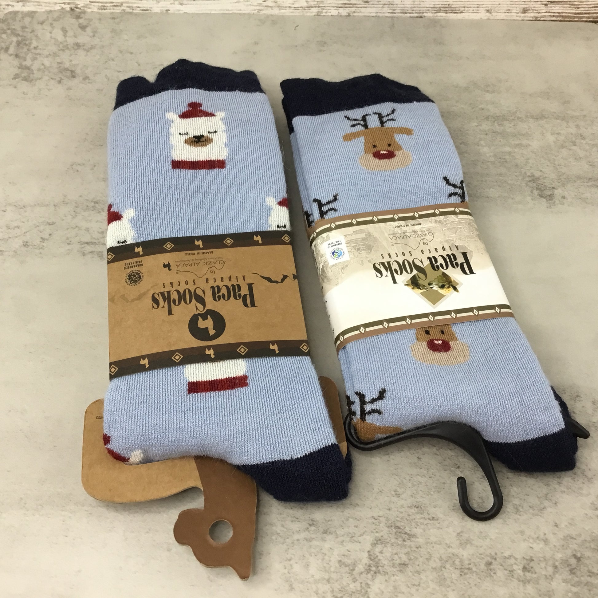 Two pairs of alpaca novelty socks with animal designs on a gray surface.