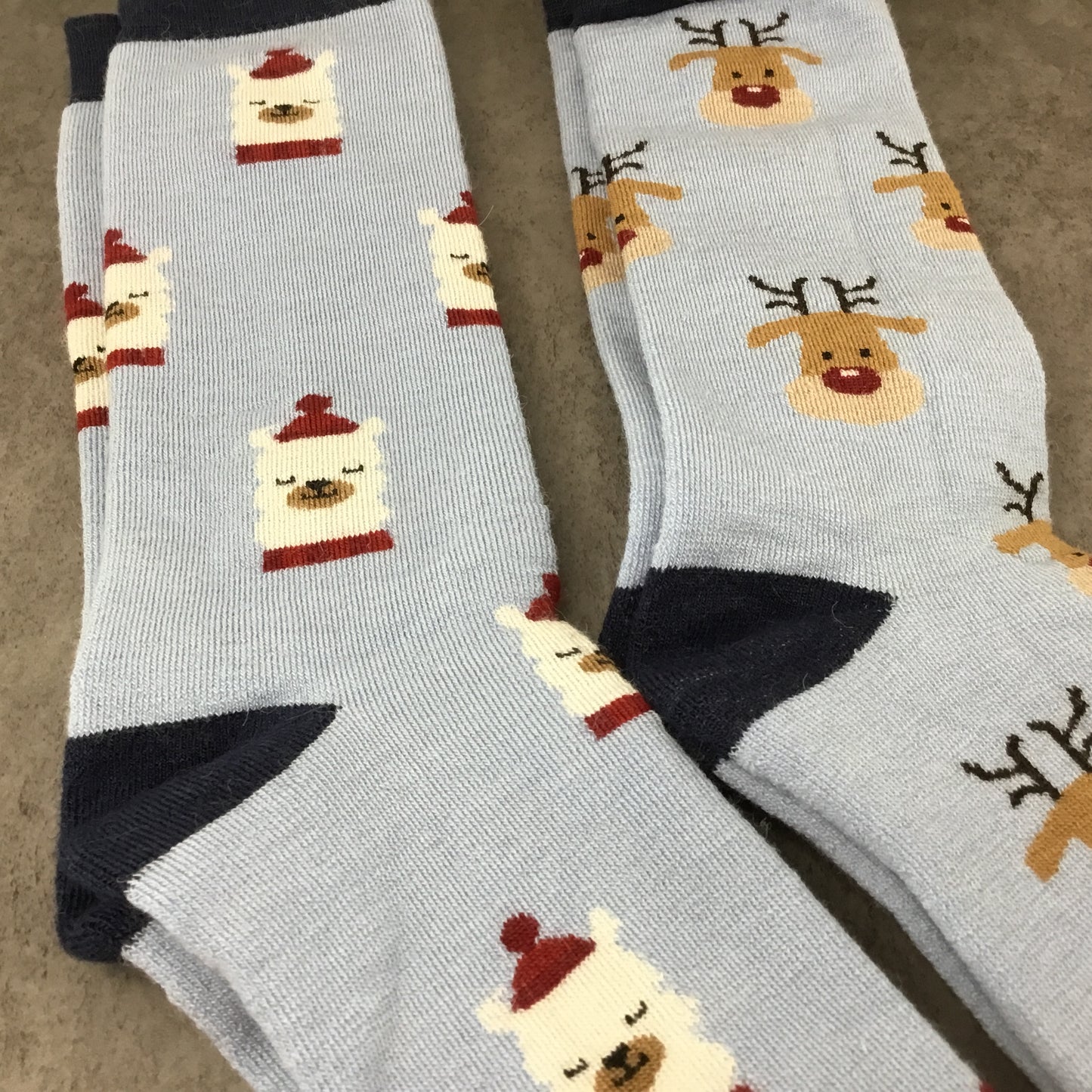 Gray socks with reindeer and Santa Alpaca designs on a neutral background