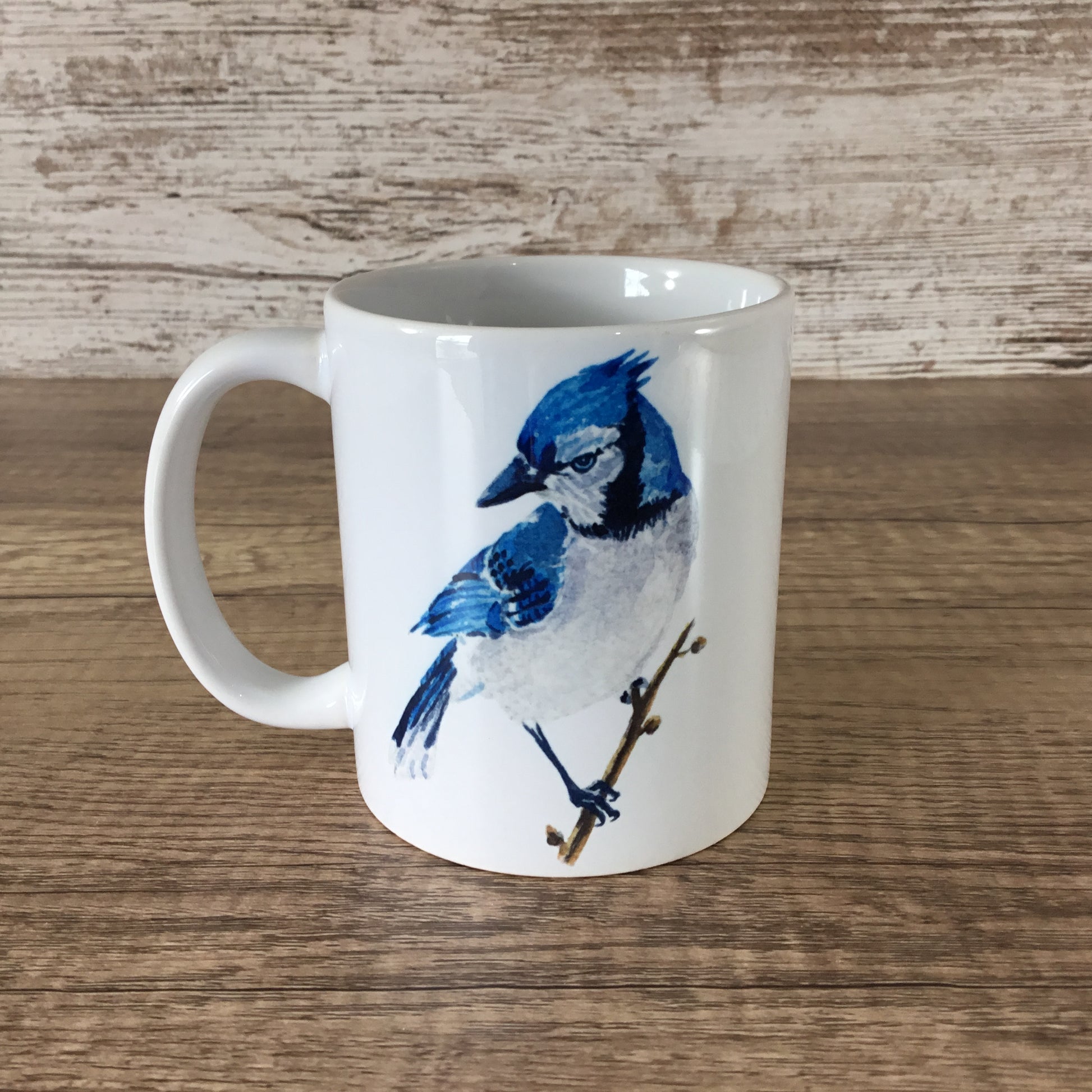 White mug with a blue jay design on a wooden surface