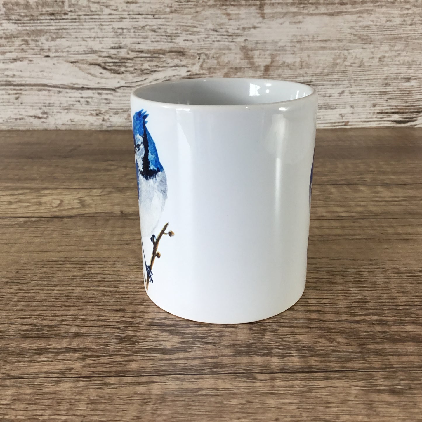 White mug with a blue jay design on a wooden surface