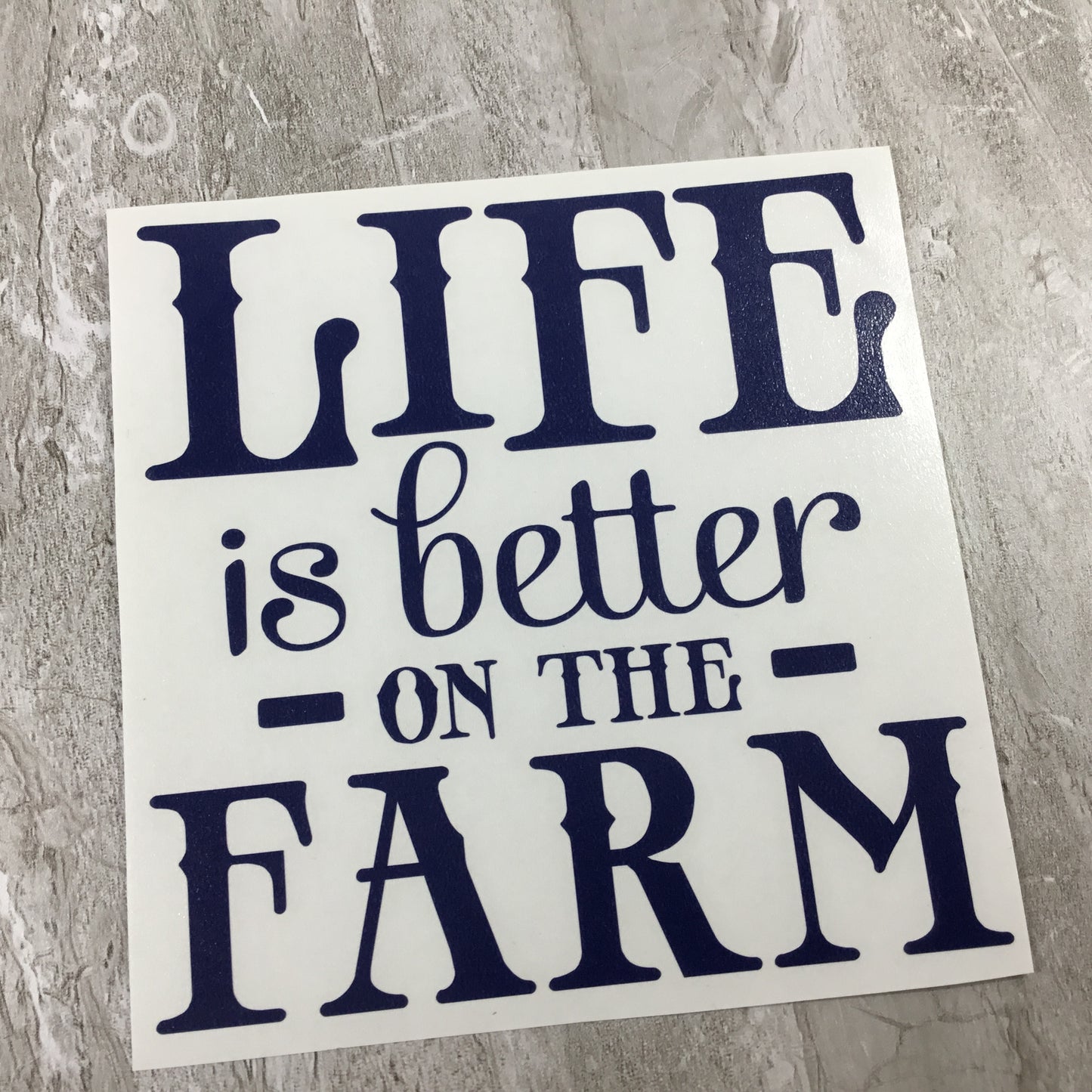 Sticker with 'Life is better on the farm' text on a textured surface