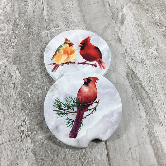 Two car coasters with cardinal bird designs on a gray surface