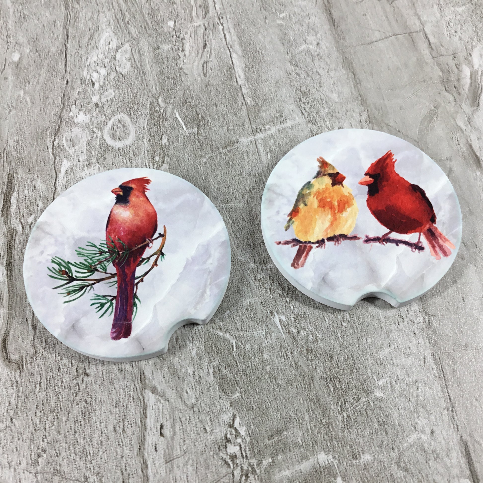 Two car coasters with bird designs on a textured surface