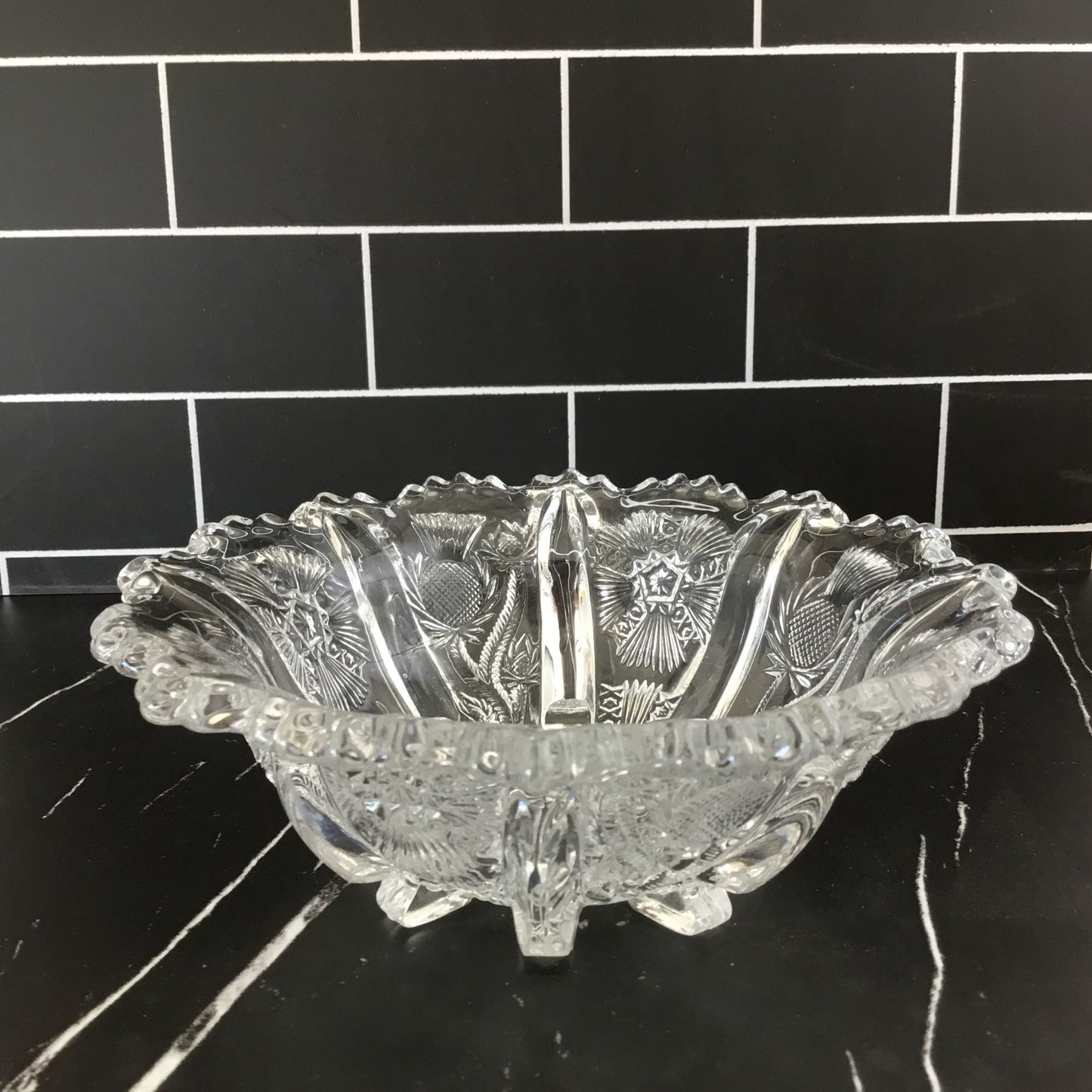 Decorative glass bowl on a black surface with a black tiled wall background