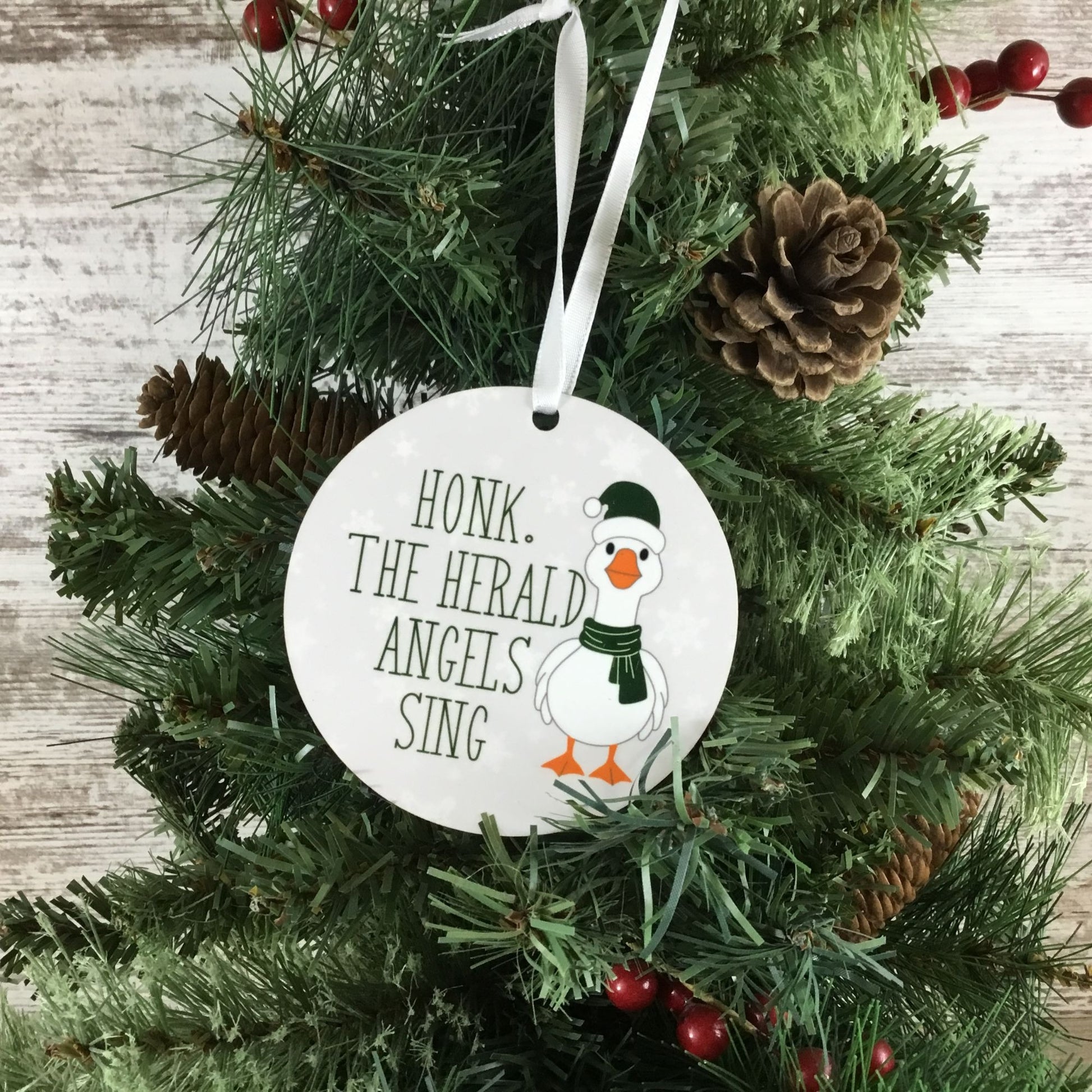 Christmas ornament with a goose design and text on a tree.
