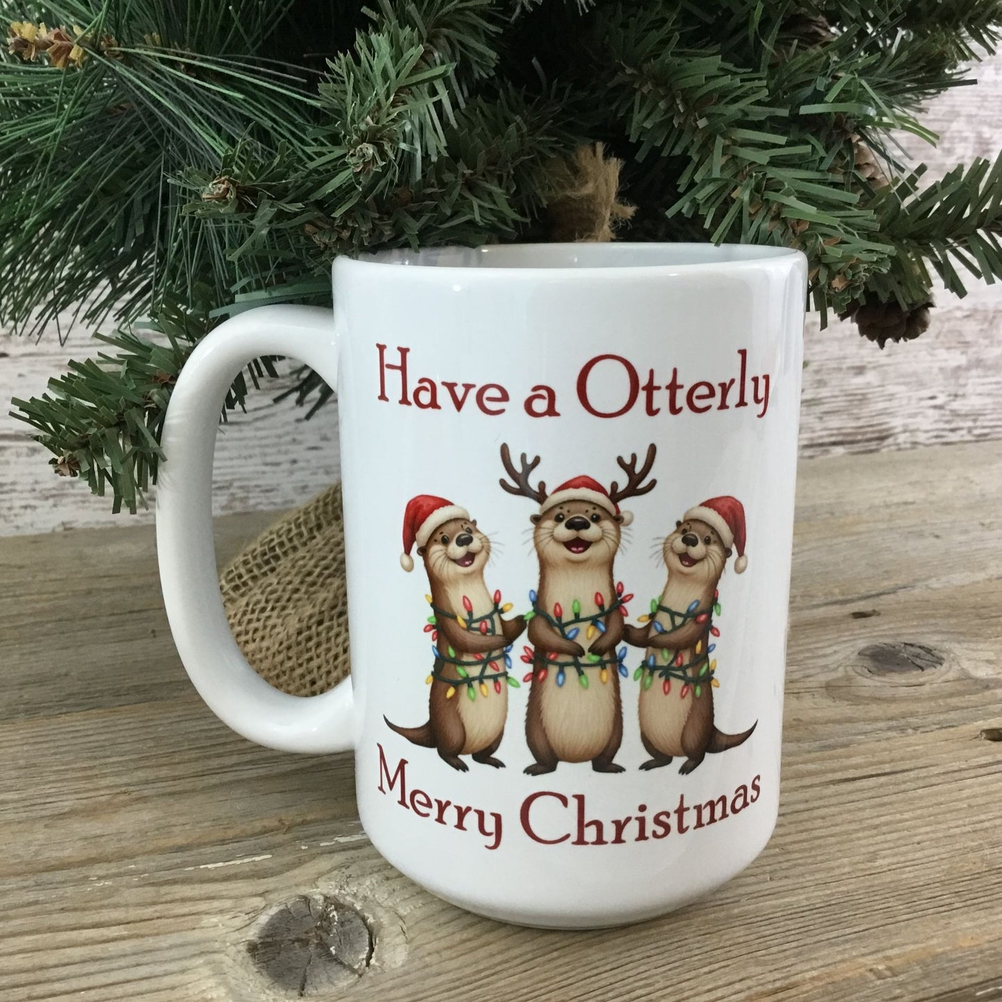 White mug with Christmas otter design and text under a tree