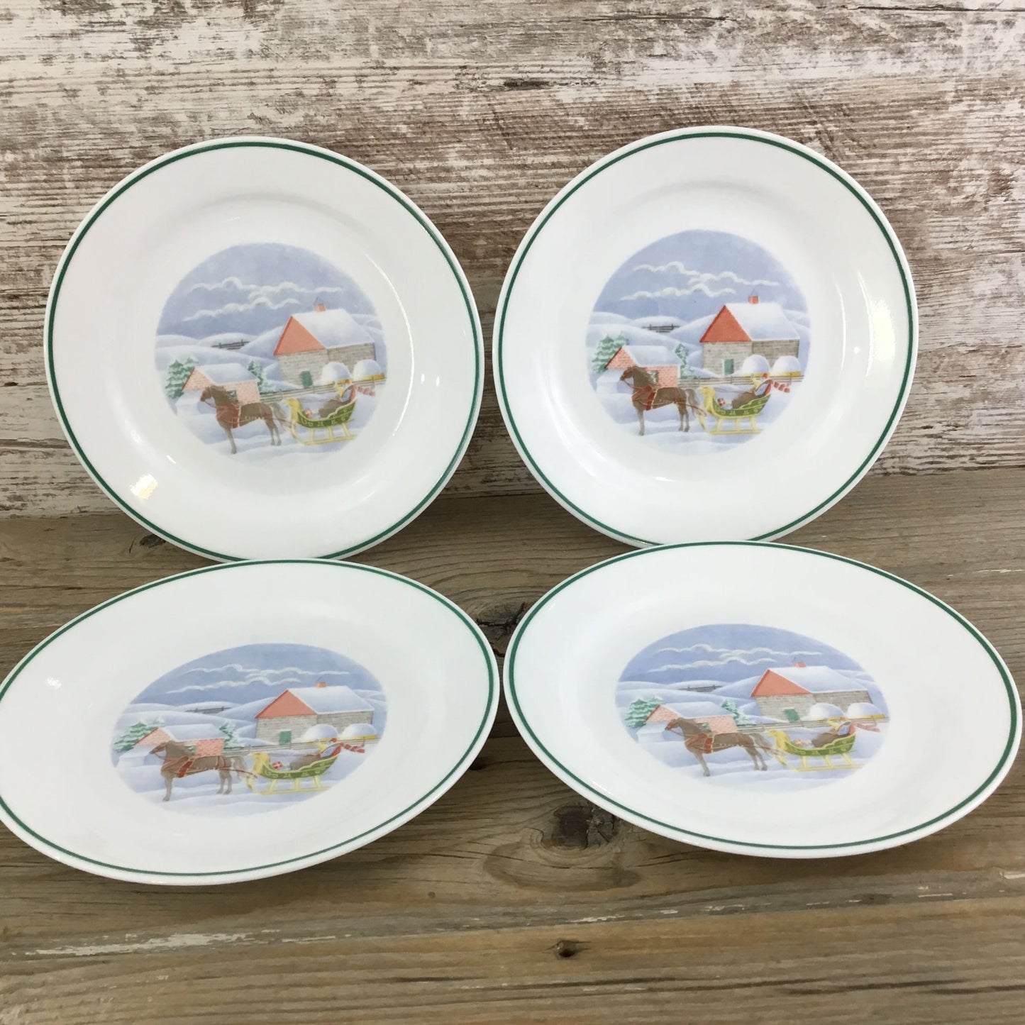 Four ceramic plates with horse illustrations on a wooden surface
