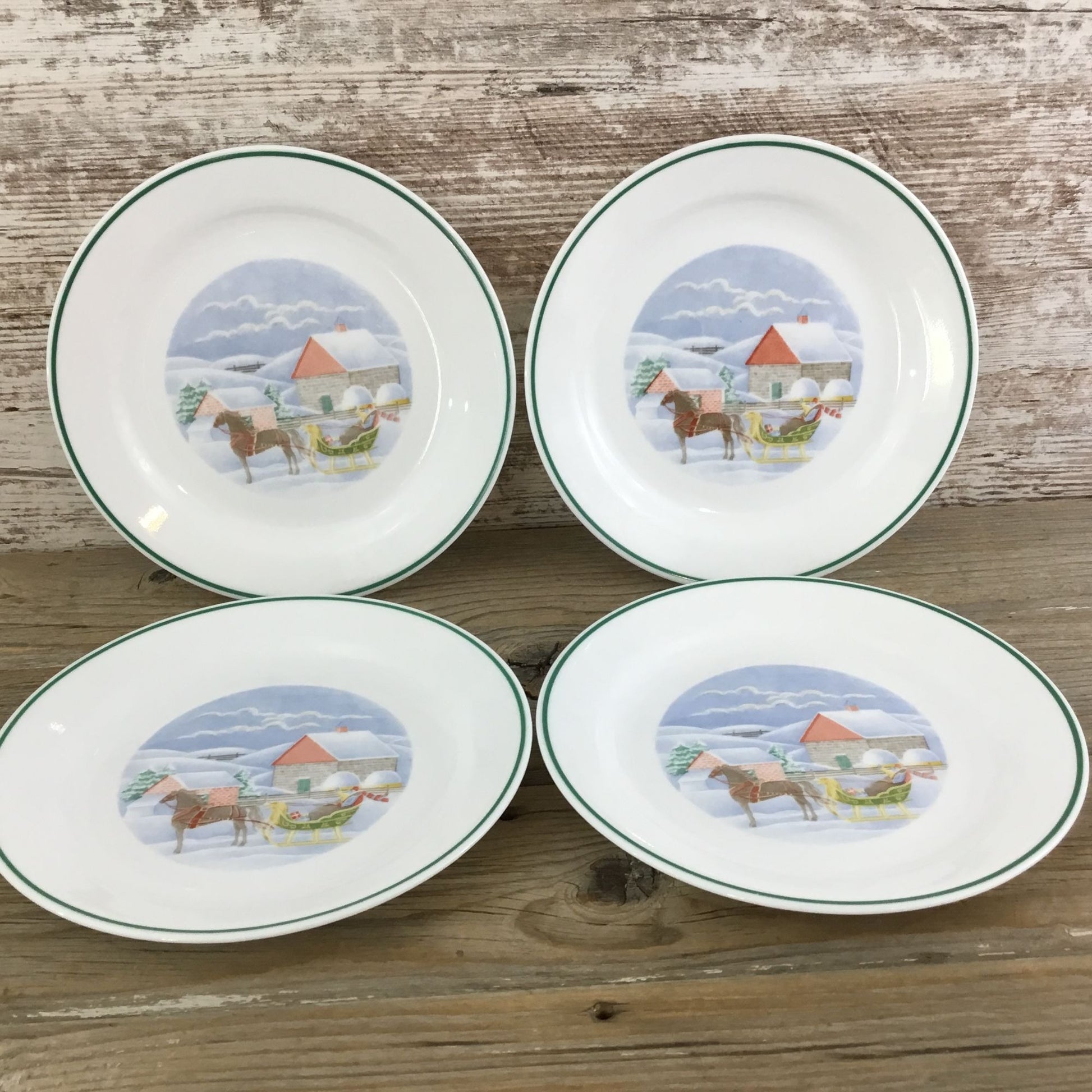 Four ceramic plates with horse illustrations on a wooden surface