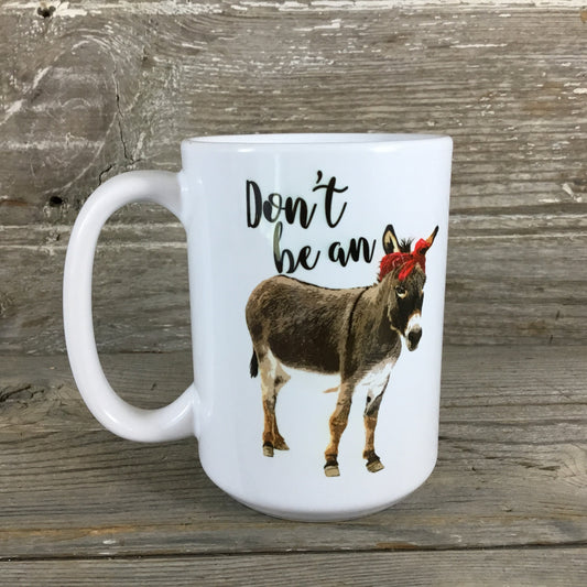 White mug with a donkey illustration and text 'Don't be an' on a wooden background