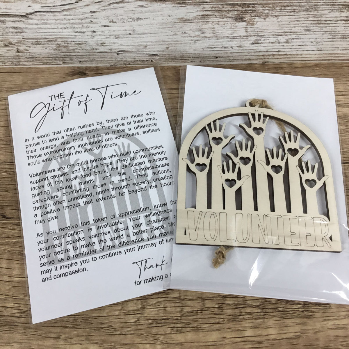 A wooden 'Volunteer' arch ornament displayed next to its printed 'The Gift of Time' message card on a light wood background.