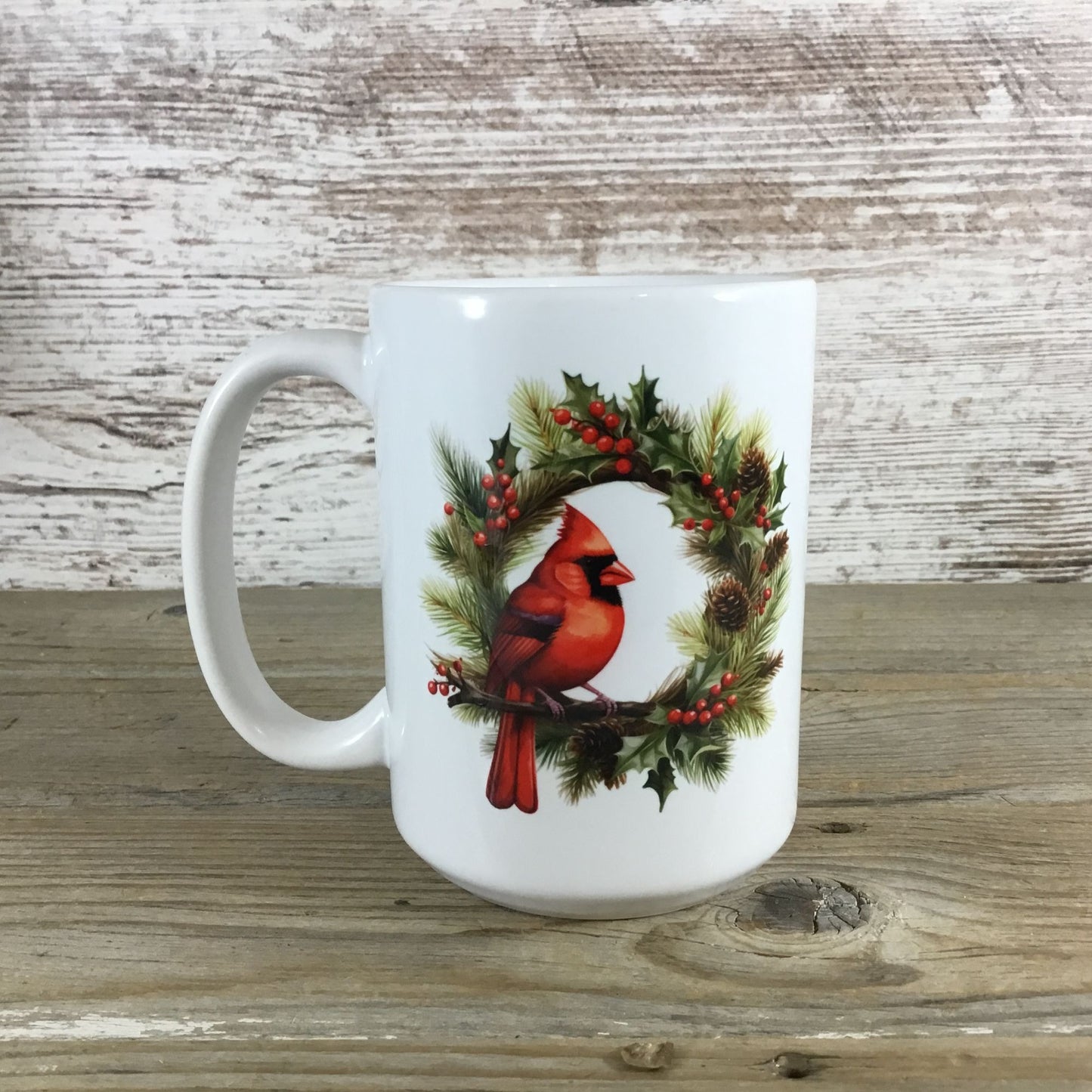 White mug with a red cardinal and holly design on a wooden surface