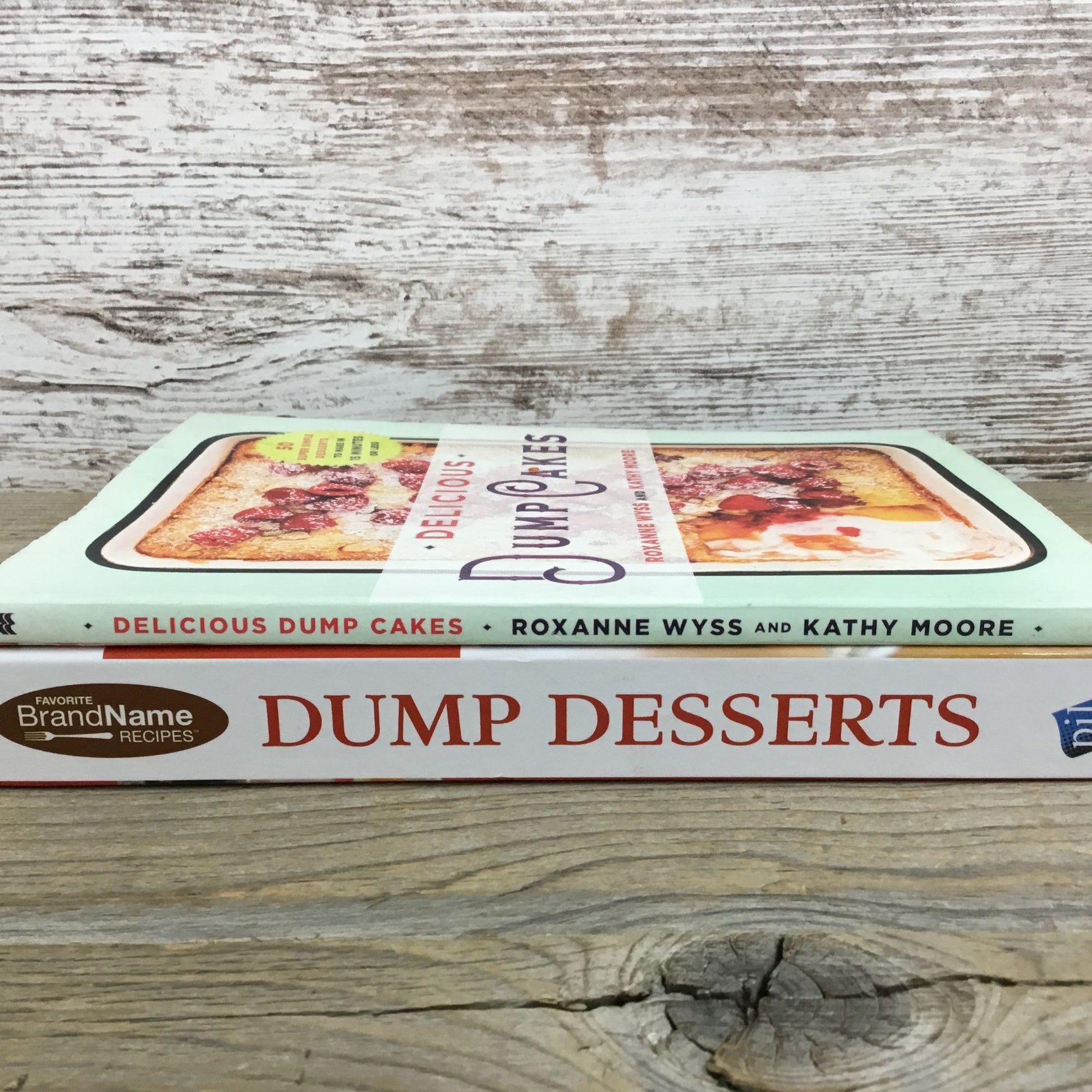 Two cookbooks titled 'Dump Desserts' and 'Delicious Dump Cakes' on a wooden surface.