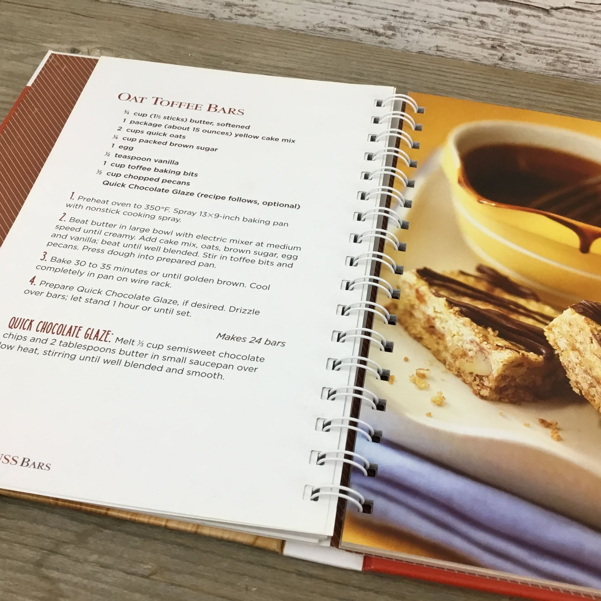 Open cookbook with a recipe for oat toffee bars and a photo of a dessert on a wooden surface.